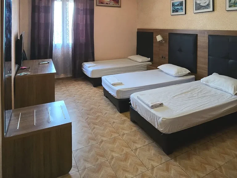 Chambre triple avec trois lits simples, bureau et télévision